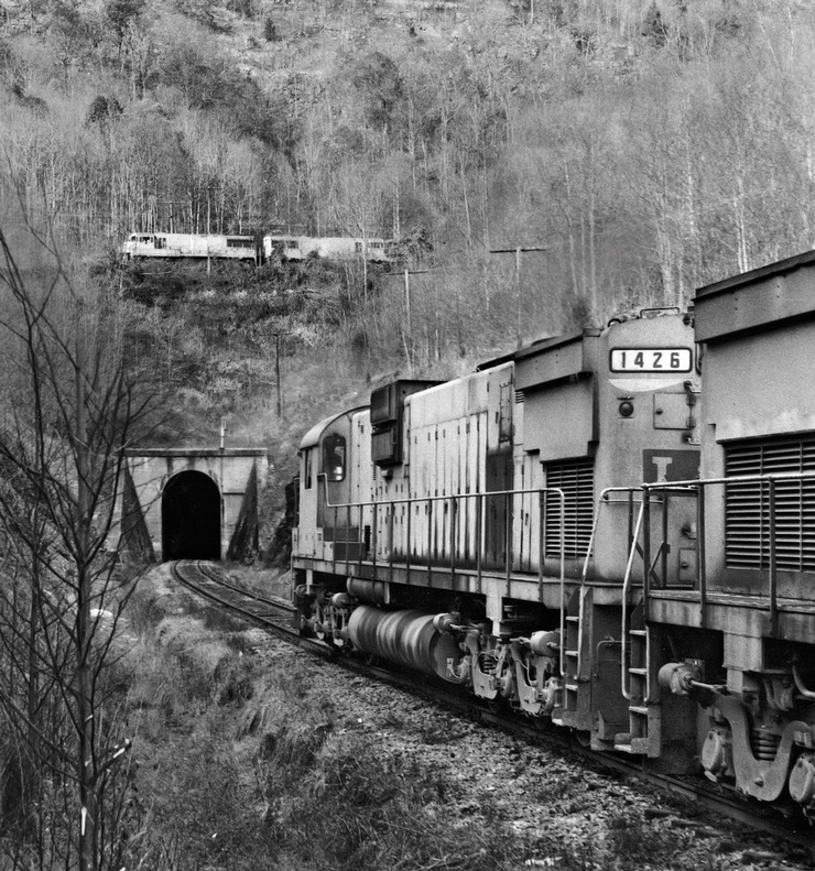 The train on the top was photographed by Everett on November 9, 1975. Train 2nd 864 is dropping downgrade into Hagans, where it will follow the lead into the middle tail track of the switchback. Everett listed the motive power as 1513-1515-1306-1316-1323 (two GE U25Cs and three Alco C420s--although the Alcos are hidden by the trees). The lower shot was taken on December 28, 1975--a few weeks after the first. L&N 1st 864 was led by 1426-1412-1513 (an Alco C630, C628, and a U25C--in the fact the same unit pictured on the upper train from the previous month). Everett noted the lower train had 75 cars.