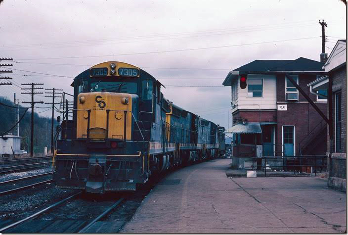 Having retrieved a extended-cupola caboose, they head back into the yard. Note the dwarf hanging on the cantilever bracket in front of the depot. Dwarfs, semaphores, position light and color light signals – Russell had them all at the east end. 11-10-1977. RU Cabin