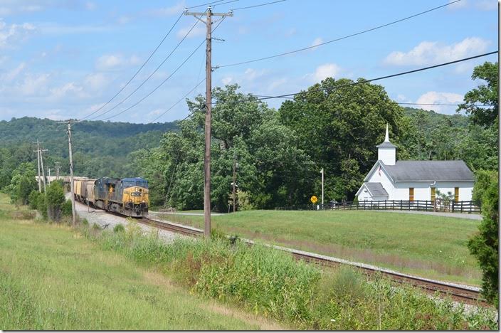 CSX e/b grain train behind 128-987 rolls by the picturesque Methodist church at Kavanaugh KY, on the Big Sandy SD. 06-21-2015. CSX 128-987 Kavanaugh KY. View 2.