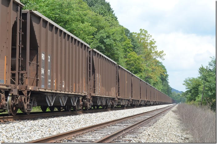 Rock train 68Q-23 is parked on the Princeton-Deepwater District (ex-VGN) main at Kellysville WV. This train of 67 loads of scrubber stone is headed from Boxley’s load-out in Princeton Yard to the CP&L/Progress Energy power plant at Hyco NC. The ROKX reporting mark belongs to the utility. 08-22-2018. ROKX 8437.