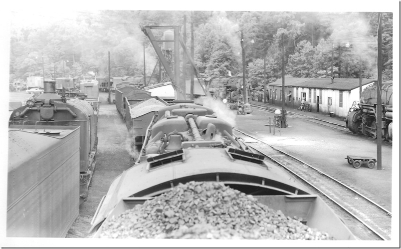 A steam derrick and tool cars are parked on the left. Wonder where they will dump those cinders? The shop buildings on the right are still used today. 05-31-1959. N&W Weller VA terminal. R. L. Harvey collection.